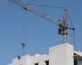 Old construction crane is lifting building materials. The construction of a multi-story building