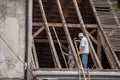 Old Construction workers, roofers and tilers, replacing and renovating the roof of a house with tiles while wooden beam plywood