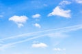 Old contrail between cumuli clouds in blue sky