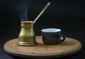 An old copper jug of steaming, aromatic coffee and a coffee cup. Royalty Free Stock Photo