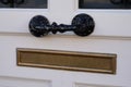 Old copper letterbox mailbox with black door handle in the white vintage wooden door in traditional way of delivering letters