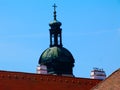 Old copper plated white church clock tower with cross. red clay sloped roofs below Royalty Free Stock Photo