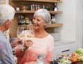 Old couple, toast and happiness in kitchen with wine for retirement, celebration and cooking in apartment. Senior woman Royalty Free Stock Photo