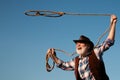 Old cowboy with lasso rope at ranch or rodeo. Bearded western man with brown jacket and hat catching horse or cow. Royalty Free Stock Photo