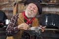 Old cowboy stirs saucepan in outdoor kitchen Royalty Free Stock Photo