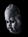 Old cracked creepy doll head isolated on black