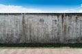 Old cracked gray cement or concrete wall with blue sky as background. Grunge plastered stucco textured background