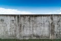 Old cracked gray cement or concrete wall with blue sky as background. Grunge plastered stucco textured background