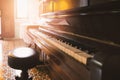 Old and cracked piano and stool with sunlight