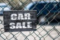 Old cracked rectangular wooden plate on the old green mesh fence with the inscription Car Sale Royalty Free Stock Photo