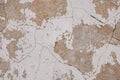 Old cracked weathered painted wall background texture. Beige dirty peeled plaster wall with falling off flakes of paint Royalty Free Stock Photo