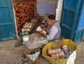 An old craftsman wrapping leather around miniature ceramic drums