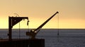 Old crane on the dock in the sunset on a pier of Chile