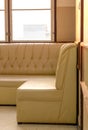 Old cream-colored sofa in the corner of the room with window light Royalty Free Stock Photo