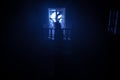 Old creepy eerie baby crib near window in dark room. Scary baby silhouette in dark. A realistic dollhouse living room with Royalty Free Stock Photo
