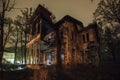 Old creepy wooden abandoned haunted ruined mansion at night