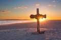 An old cross on sand dune next to the ocean with a calm sunrise Royalty Free Stock Photo