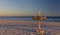 An old cross on sand dune next to the ocean with a calm sunrise Royalty Free Stock Photo