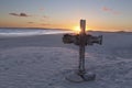 An old cross on sand dune next to the ocean with a calm sunrise Royalty Free Stock Photo