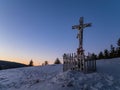 Crucifix on a snowy mountain during sunset