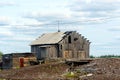 Old crumbling barn with a house standing on the background of a pile of abandoned logs