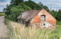 Old crumbling barn with a stone and red brick tiled roof in Latvia. Royalty Free Stock Photo