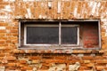 Old crumbling red brick building with small wooden windows Royalty Free Stock Photo