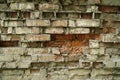 An old crumbling wall with destroyed bricks between a strong masonry mortar