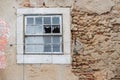 Old crumbly wall with flaking plaster and broken window, abandoned house Royalty Free Stock Photo
