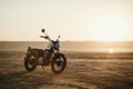 Old custom beautiful cafe racer motorcycle in the desert at sunset or sunrise Royalty Free Stock Photo