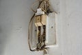 Old cut-out or circuit breaker has no cover on the white cement wall. Old electrical equipment is damaged.
