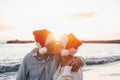 Old cute couple of mature persons enjoying and having fun together at the beach wearing christmas hats on holiday days. Hugged on Royalty Free Stock Photo