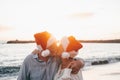 Old cute couple of mature persons enjoying and having fun together at the beach wearing christmas hats on holiday days. Hugged on Royalty Free Stock Photo