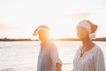 Old cute couple of mature persons enjoying and having fun together at the beach wearing christmas hats on holiday days. Walking on Royalty Free Stock Photo