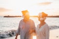 Old cute couple of mature persons enjoying and having fun together at the beach wearing christmas hats on holiday days. Walking on Royalty Free Stock Photo