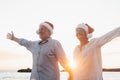 Old cute couple of mature persons enjoying and having fun together at the beach wearing christmas hats on holiday days. Walking on Royalty Free Stock Photo