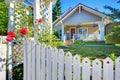 OLd cute grey house exterior behind white fence.