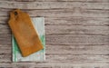 An old cutting board made of birch wood and a white and green linen napkin on a brown wooden background. Royalty Free Stock Photo