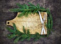 Old cutting board with spruce branches on a wooden background with fork and knife kitchen cooking christmas Royalty Free Stock Photo