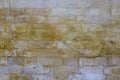 Old damaged gray wall of large bricks with bright yellow spots of paint. rough surface texture Royalty Free Stock Photo