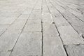 Old and damaged italian paving made with chiseled grey sandstone blocks
