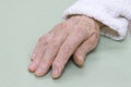Old damaged leather of a very old woman`s hand in a white bathrobe on a light background. Royalty Free Stock Photo
