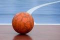 Old and damaged orange ball at futsal court. Royalty Free Stock Photo