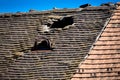 Old damaged tiled roof with a hole on the roof and broken tiles