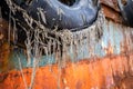 Old, damaged tyre fender with lines sticking out, on a steel hull of an abandoned cargo shipwreck