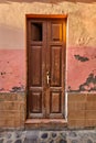 Old damaged wooden door of an abandoned weathered building. Vintage broken and aged entrance to a house in a small Royalty Free Stock Photo