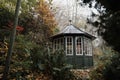 Old dark green gazebo in autumn garden. Little wooden garden shelter, cabin with wet roof. Beautiful moody, foggy Royalty Free Stock Photo