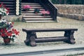 An old dark and low wooden bench on the background of a wooden ladder. There are pots of petunia flowers on the ladders. Royalty Free Stock Photo