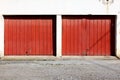Old dark red metal double garage doors with rusted patches and small door handles mounted on dilapidated garage building wall Royalty Free Stock Photo
