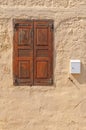 Old dark red wooden window on yellow cement textured house wall Royalty Free Stock Photo